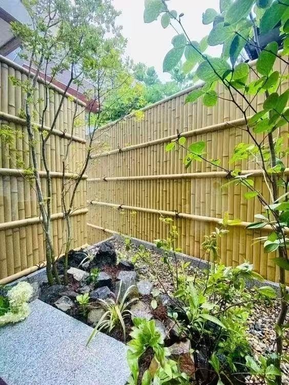 Faux bamboo trim installed on a tall bamboo-style fence in a Japanese-inspired garden walkway.